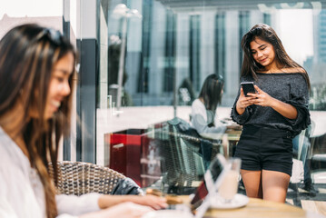 Cheerful Asian woman using smartphone in cafe