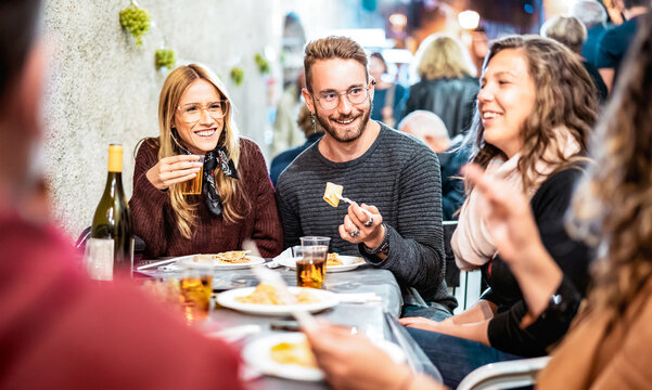 Trendy people having fun drinking white wine at street food event - Happy friends eating local meal plates at open air restaurant together - Food and beverage life style concept on bulb light filter