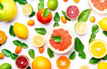Citrus fruit food background, top view. Mix of different whole and sliced fruits: orange, grapefruit, lime and other with leaves on  white table