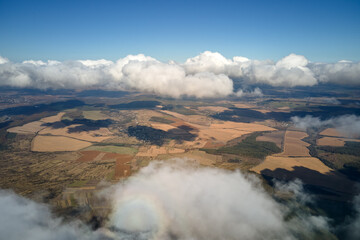 Aerial view from airplane window at high altitude of earth covered with white puffy cumulus clouds