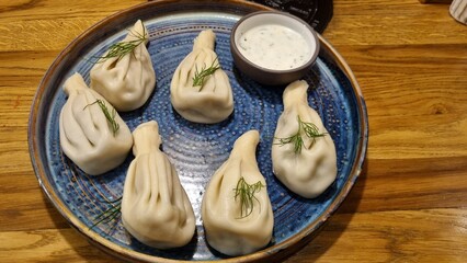 Khinkali and sour cream sauce on a platter in a Caucasian cuisine restaurant.