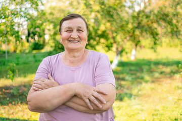 Naklejka na ściany i meble Portrait of senior woman smiling and looking at camera. Cheerful mature woman in the village. Carefree and positive retired woman.