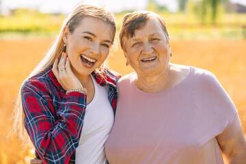 Fototapeta premium Happy girl and her grandmother have fun in the wheat field. Family, lifestyle concept