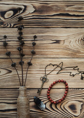 Magic stuff on wooden background, a key, black quartz, bottle, dry herb and jasper bracelet, vertical photo.