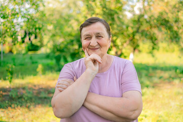 Fototapeta premium Portrait of a smiling elderly woman. A photo on the nature background