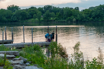 Obraz premium Family On The River Dock During A Summer Sunset