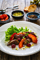 Fried liver with apples and onion on wooden table
