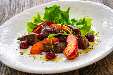 Fried liver with apples and onion on wooden table
