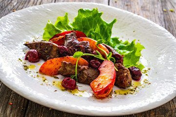 Fried liver with apples and onion on wooden table
