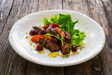 Fried liver with apples and onion on wooden table
