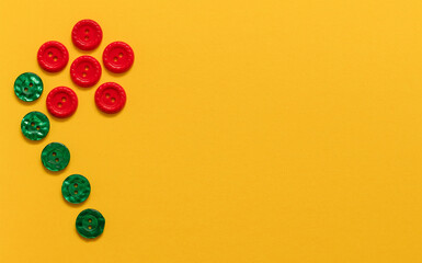 Daisy flower made from orange and green sewing buttons on a yellow background. Top view. Copy space.