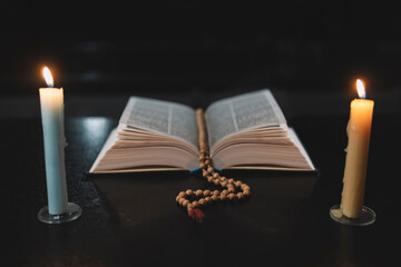 Bible and three burning candles on black table. Christian sermon. Christian faith. Protestantism, Catholicism and Orthodoxy. Faith in Jesus Christ. Study of the word of God.