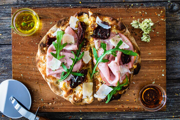 Pinsa Romana with mortadella, parmesan cheese and vegetables on wooden table
