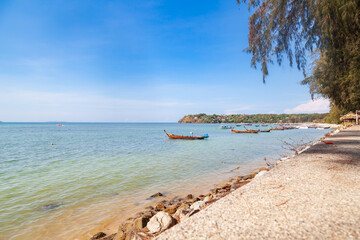 Pier Rawai beach in thailand on the island of phuket with old fishing wooden boats with long ropes moored to the shore.