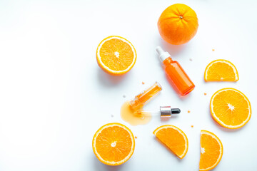 Vitamin C face skin care cosmetic concept - organic serum in a bottle and orange slices on white background.