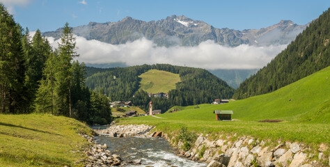 Summer view on the charming Austrian village Umhausen with the rive ötz in the foreground and...