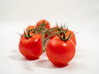 Bunch of fresh red tomatoes with green stems isolated on white background.