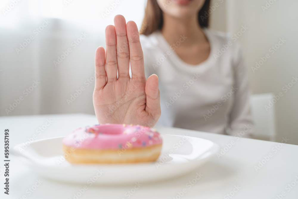 Wall mural Young woman decision to stop eating sweet snack for slim and health