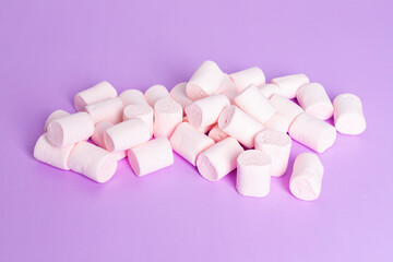 Soft sweet cylindrical marshmallows isolated on a purple background.