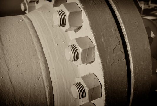 Connecting bolts of the flange connection of the main gas pipeline, close-up, black and white picture, sepia.
