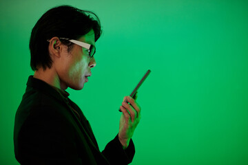 Pensive man reading text messages in smartphone, isolated on green background