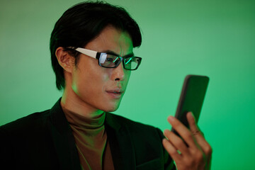 Serious man in glasses checking notifications in smartphone