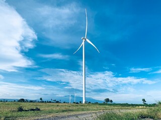 A wind turbine in a field with clouds in the background