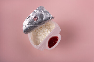 Grainy cottage cheese with strawberry jam on a pink background, top view