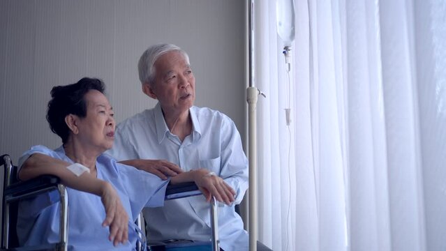 Asian senior couple supporting talking wife in hospital on wheelchair age and health promblem