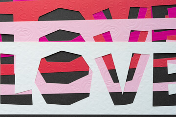 paper sign with the word "love" cut from scrapbook paper with embossed valentine or love themed elements