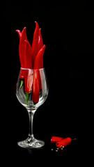 Red chili pepper in a glass on a black background.