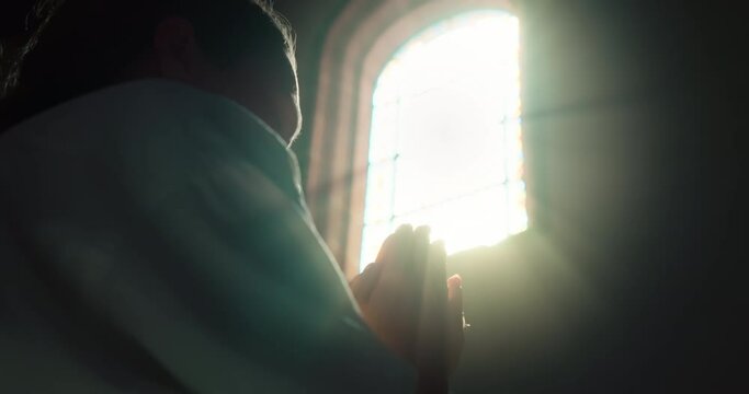 Woman head bowed in prayer to Christ the Redeemer in church. Close-up girl folded hands in prayer.
