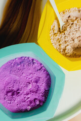 Hair dye of different colors (purple and yellow) in the form of a powder stands on a table in a beauty salon