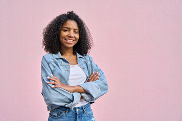 Young stylish woman model pose in denim jacket in front of soft pink background looking at camera....