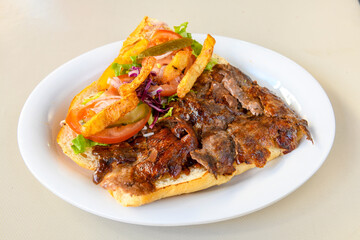Turkish and Arabic Traditional Ramadan doner kebab with tasty tomato sauce and rice or turkish pilav in white plate on wood table background. ( Pilav ustu doner)