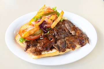 Turkish and Arabic Traditional Ramadan doner kebab with tasty tomato sauce and rice or turkish pilav in white plate on wood table background. ( Pilav ustu doner)