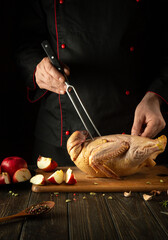 The cook prepares Peking duck in the kitchen of the restaurant. Delicious duck with apples for lunch by chef's hands
