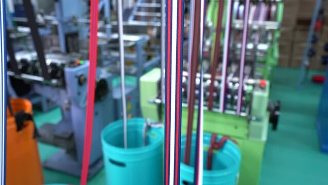 Thread from weaving machine. The mechanical equipment of the plastic weaving production line is running in a factory. Industrial narrow woven production line. Weaving looms in a textile factory.