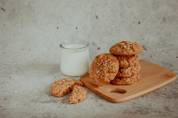 Oatmeal cookies with milk on light background with crumbs