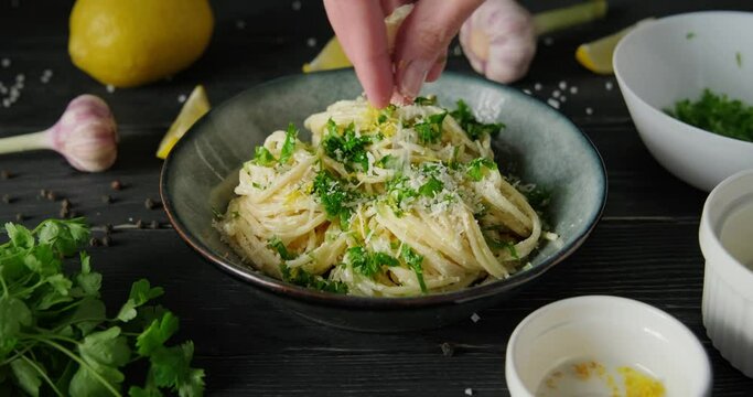 Sprinkling lemon pasta with parmesan cheese topping, person preparing spaghetti with white alfredo sauce, serving pasta for dinner, 4k footage, high quality horizontal video clip