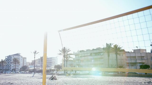 Up-close view of a beach volleyball net, illuminated by the sun's glare, with a vibrant summertime feel