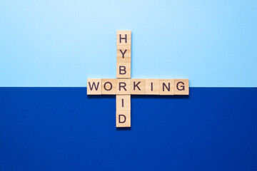 Words Hybrid working from wooden blocks with letters on dark and light blue background. Place for...