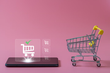 shopping online and e-commerce concept. A small empty shopping cart and Online shopping icon on smartphone on pink background. Online payment and Internet banking on mobile phone application.