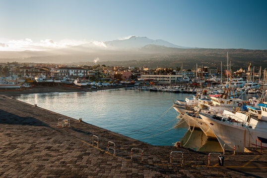 The harbor of Riposto during the sunset; snowy volcano Etna in the background