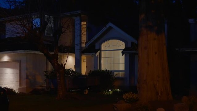 Establishing shot of two story stucco luxury house with garage door, big tree and nice landscape at night in Vancouver, Canada, North America. Night time on Apr 2023. ProRes 422 HQ.