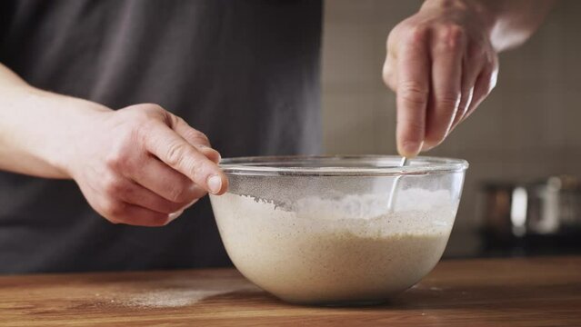 A man making poffertjes at home - mixing salt in batter. Traditional Dutch mini pancakes with buckwheat flour, white flour, egg and milk.