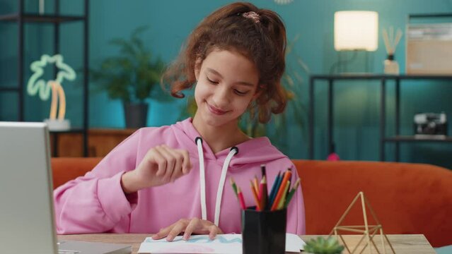 Preteen school girl drawing colorful picture I Love Mom with pencils on white paper, greeting card surprise for mother. Happy Mother's Day. Young child, kid at home workplace sitting at the table
