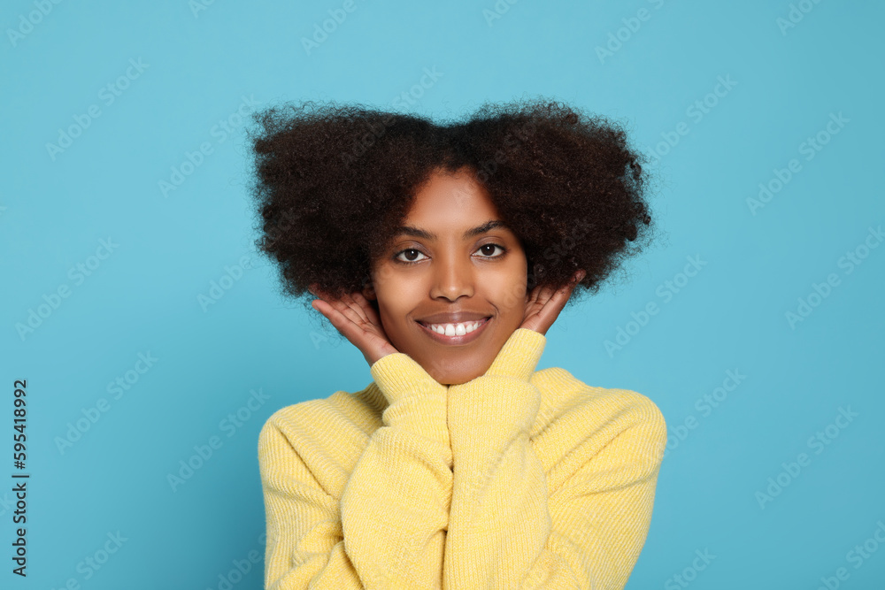 Wall mural Portrait of smiling African American woman on light blue background