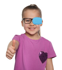 Girl with eye patch on glasses showing thumb up against white background. Strabismus treatment