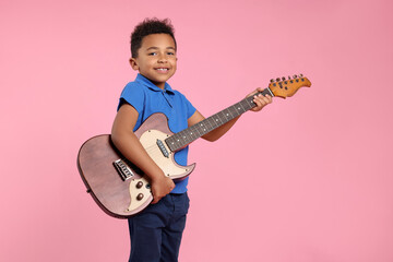 African-American boy with electric guitar on pink background. Space for text